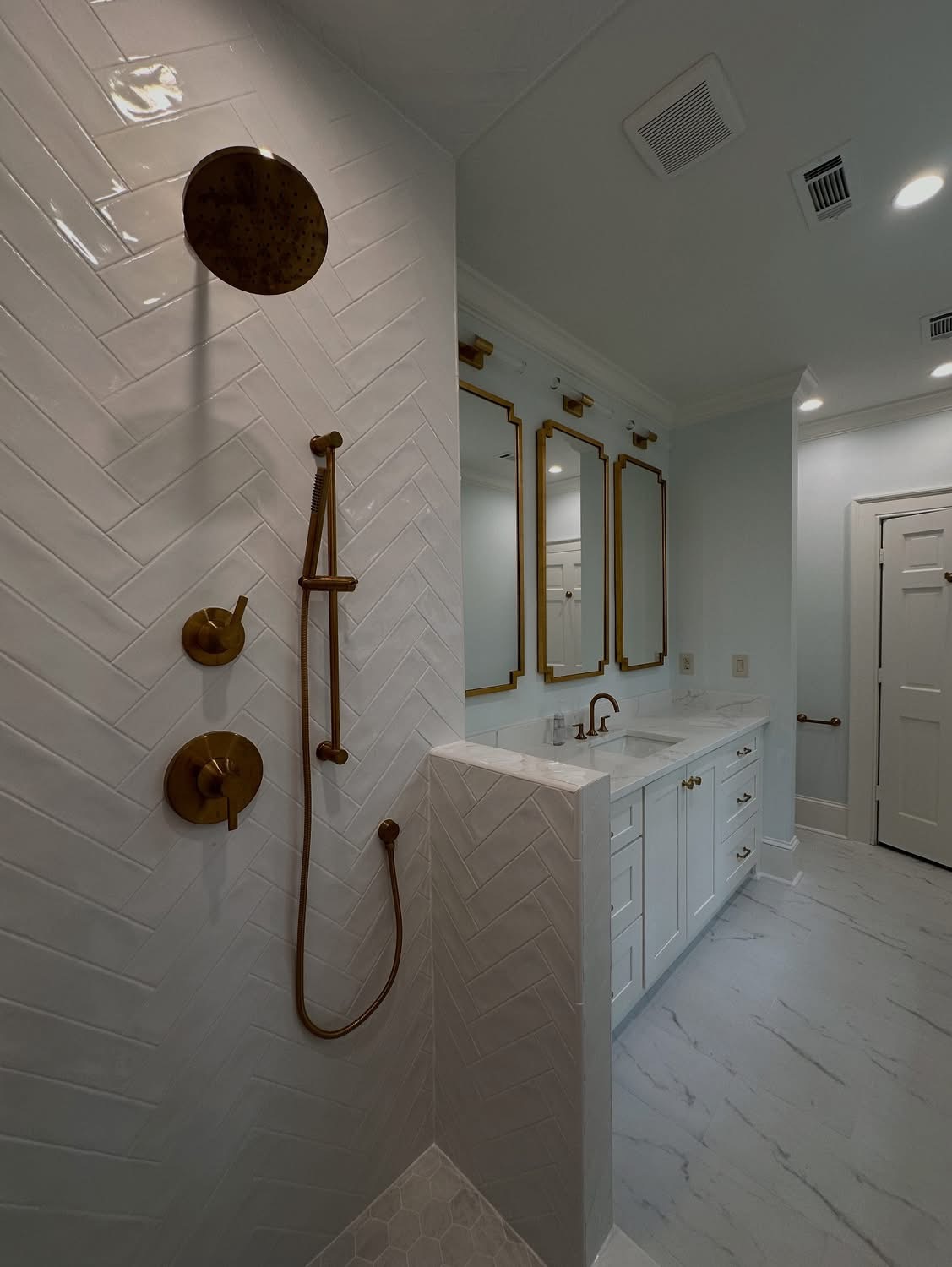 Modern bathroom with herringbone tile and gold fixtures