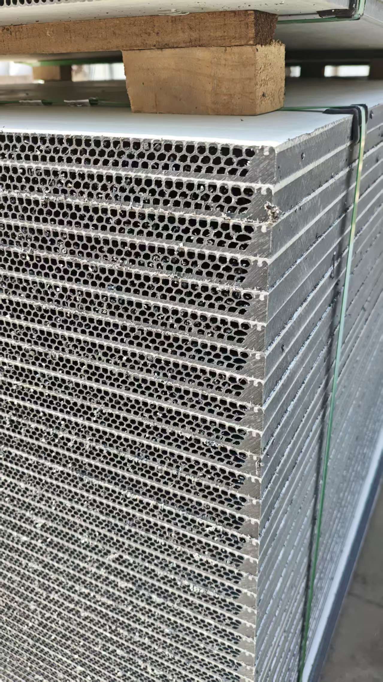 PP hollow plastic formwork panels with honeycomb surface stacked on wooden pallets, secured with green strapping bands in warehouse
