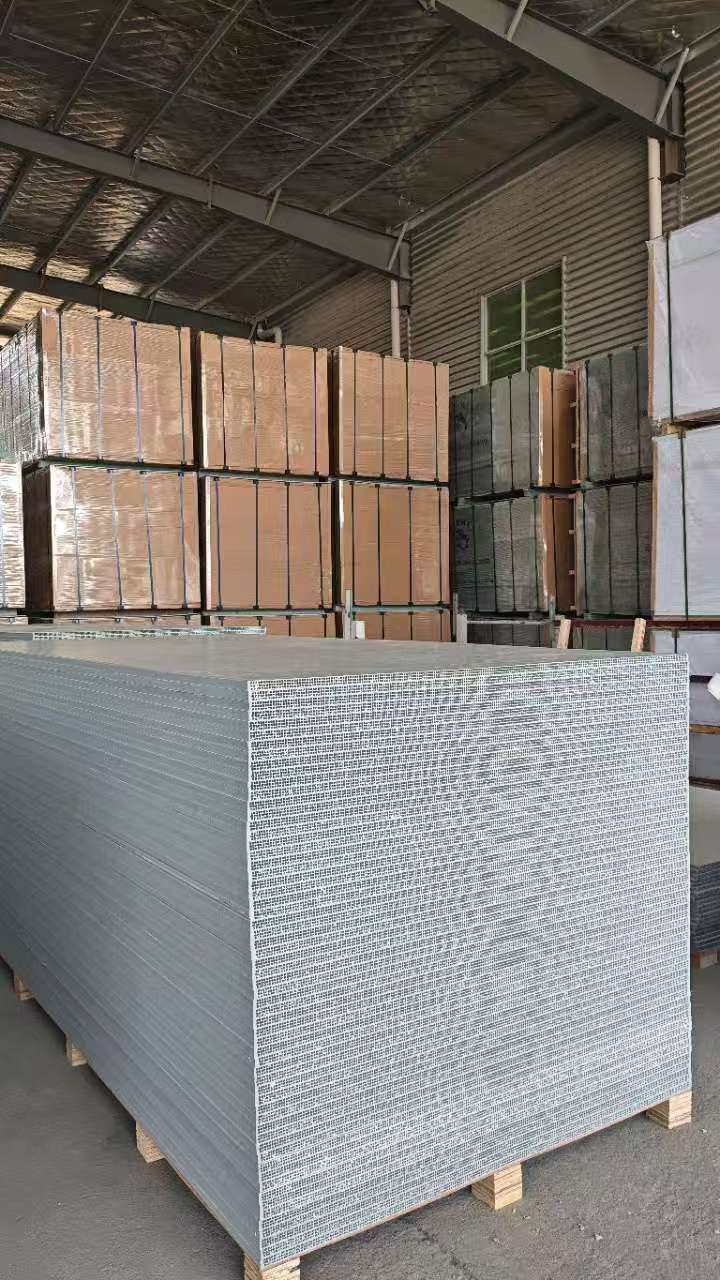PP hollow plastic formwork panel with grid texture placed on wooden pallet, wrapped panel bundles stacked in warehouse background