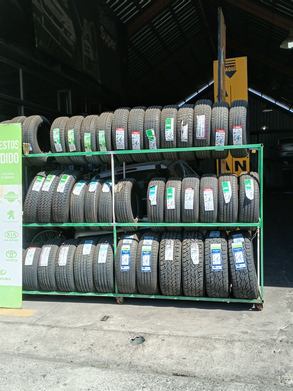 Exhibición exterior de neumáticos en estanterías verdes