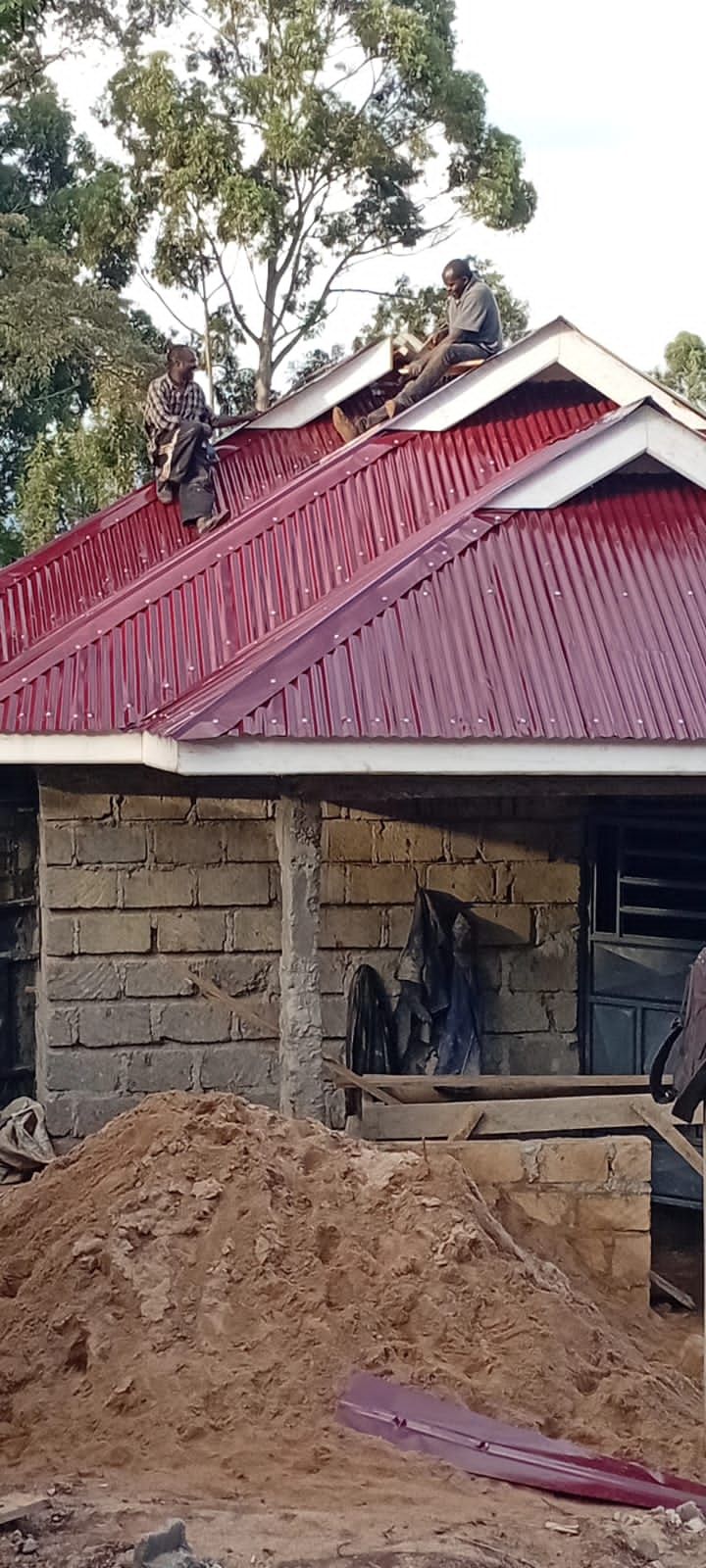 Workers on red corrugated roof