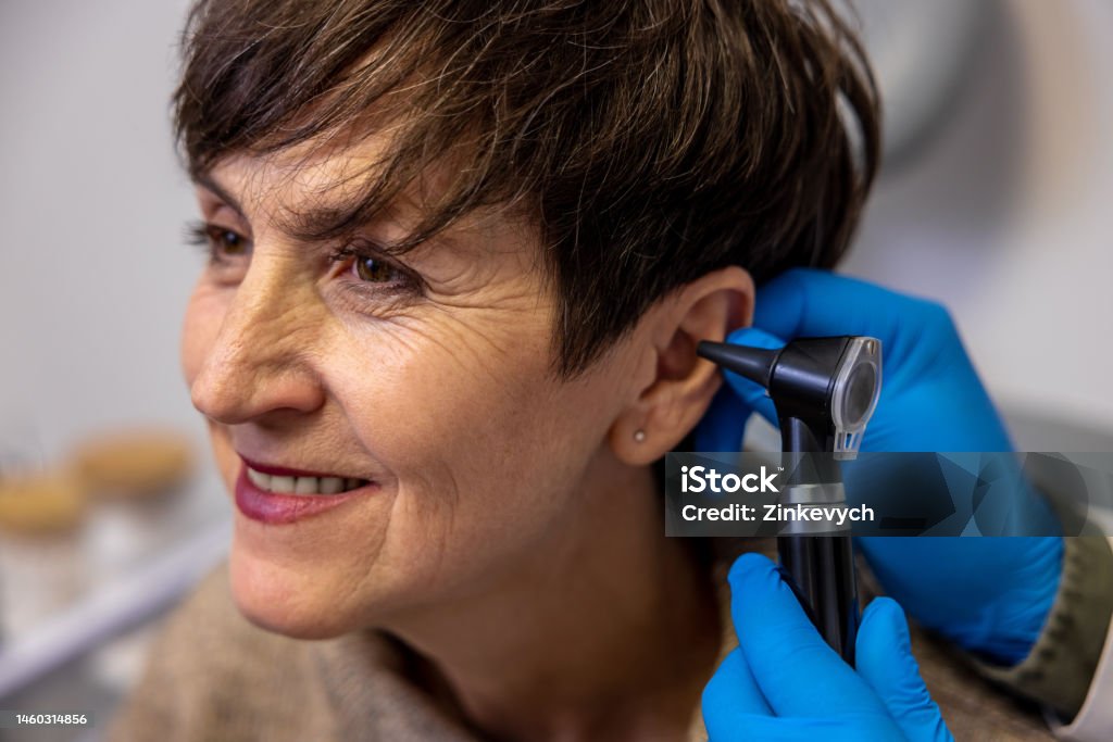 Doctor examining a patient's ear with medical instruments at HearPlus