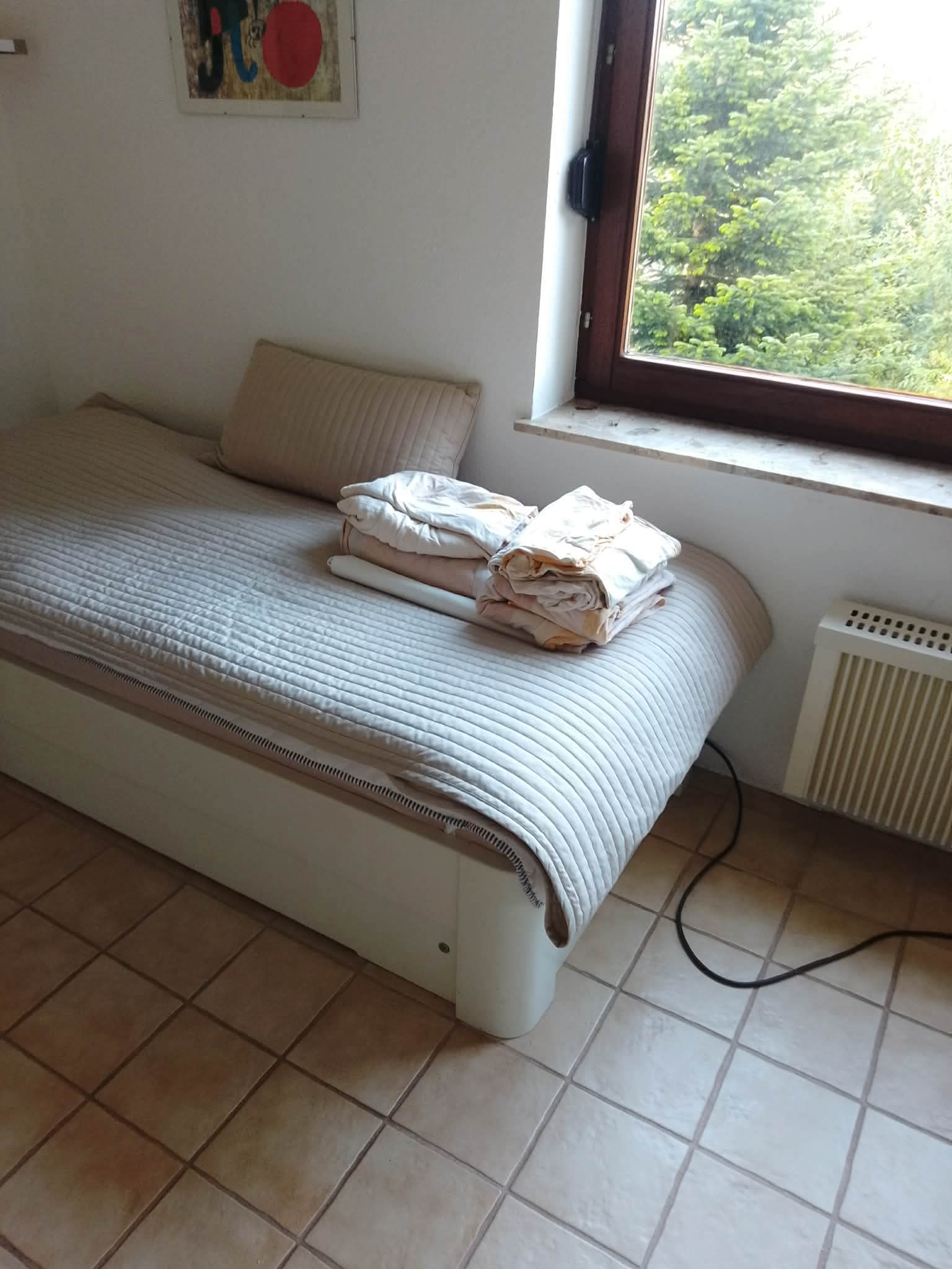 Aufgeräumtes Einzelbett mit Fensterblick