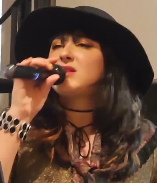 Laís Félix cantando com microfone