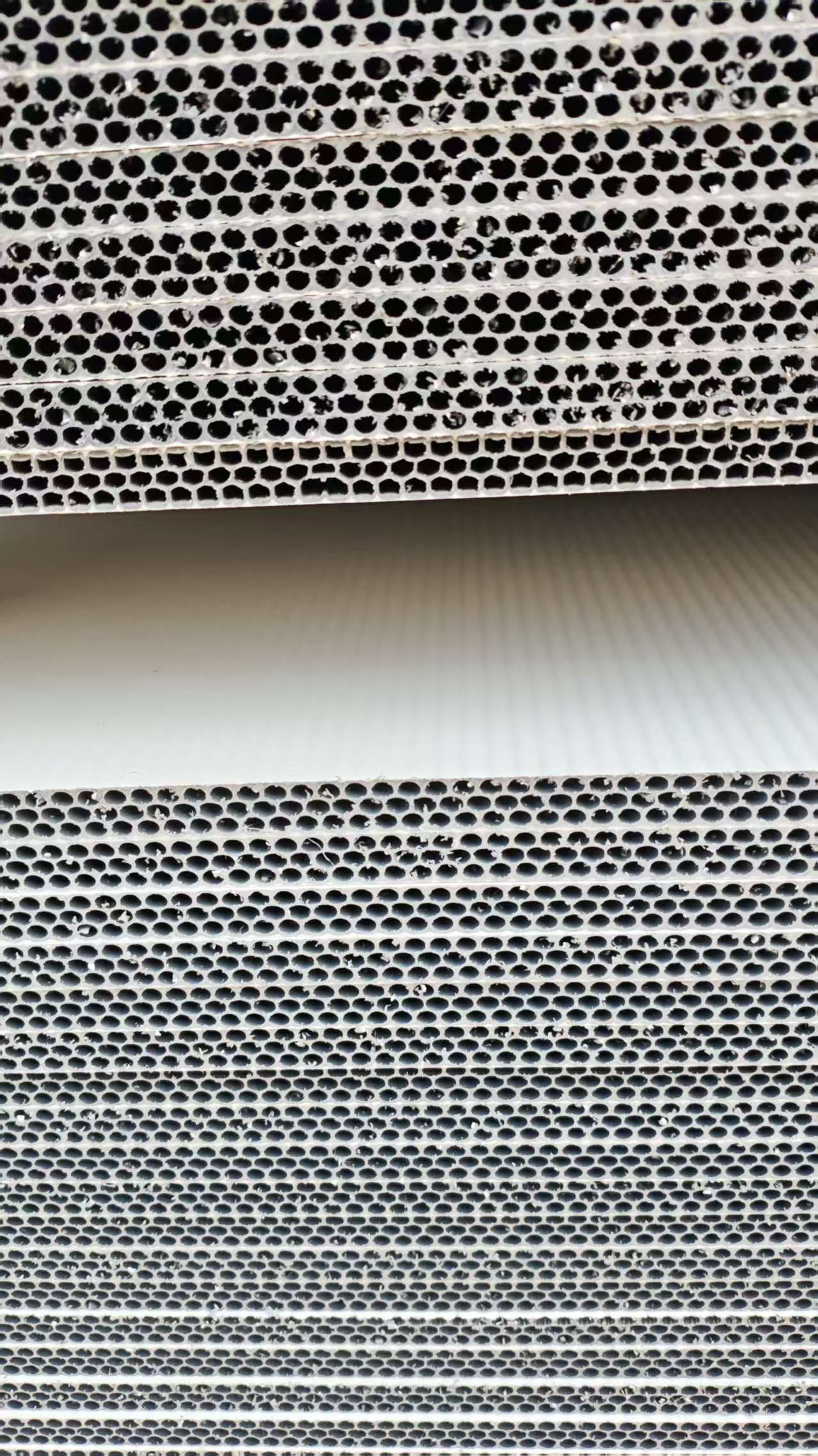 Close-up of PP hollow plastic formwork showing uniform circular hollow core holes in silver-gray polypropylene material