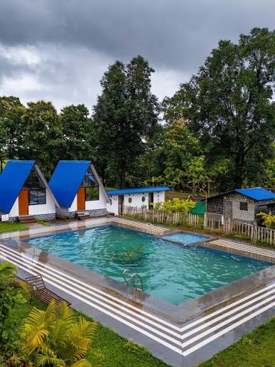 Areca Jungle Stay resort in Dandeli with swimming pool, blue-roofed cottages surrounded by lush tropical trees
