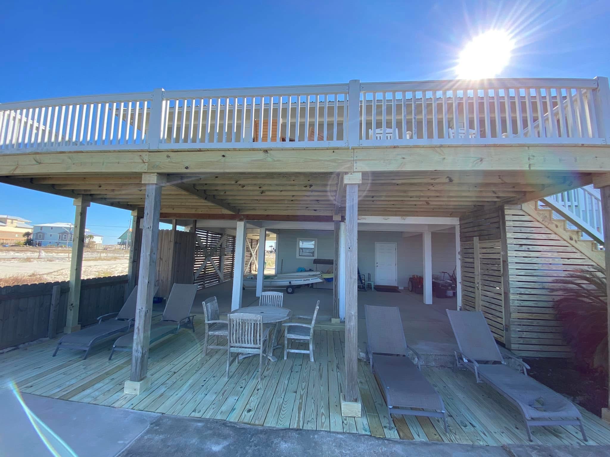 Seaside wooden cabin with upper deck and lower patio built by The Handyman Guys LLC, showcasing coastal carpentry craftsmanship