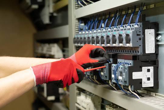 Wartung am Schaltschrank mit Handschuhen