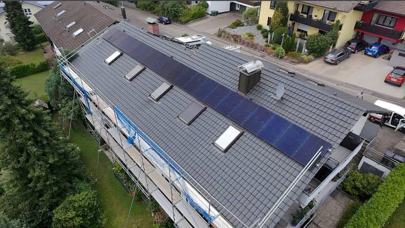 Dach mit blauen Solarpaneelen in einem Wohngebiet