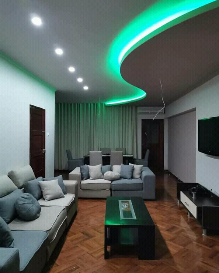 Sala de estar com tecto falso e tecto em onda com LED verde