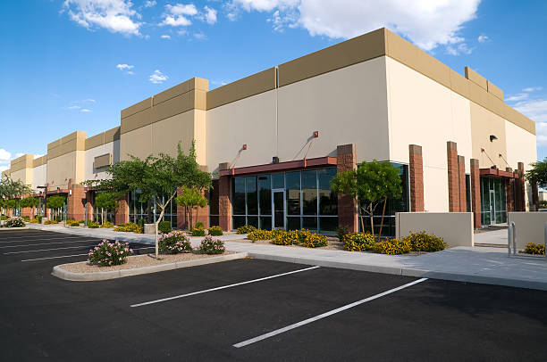 Modern commercial retail center building with brick and glass facade, clean parking lot with landscaping trees and shrubs in clear weather