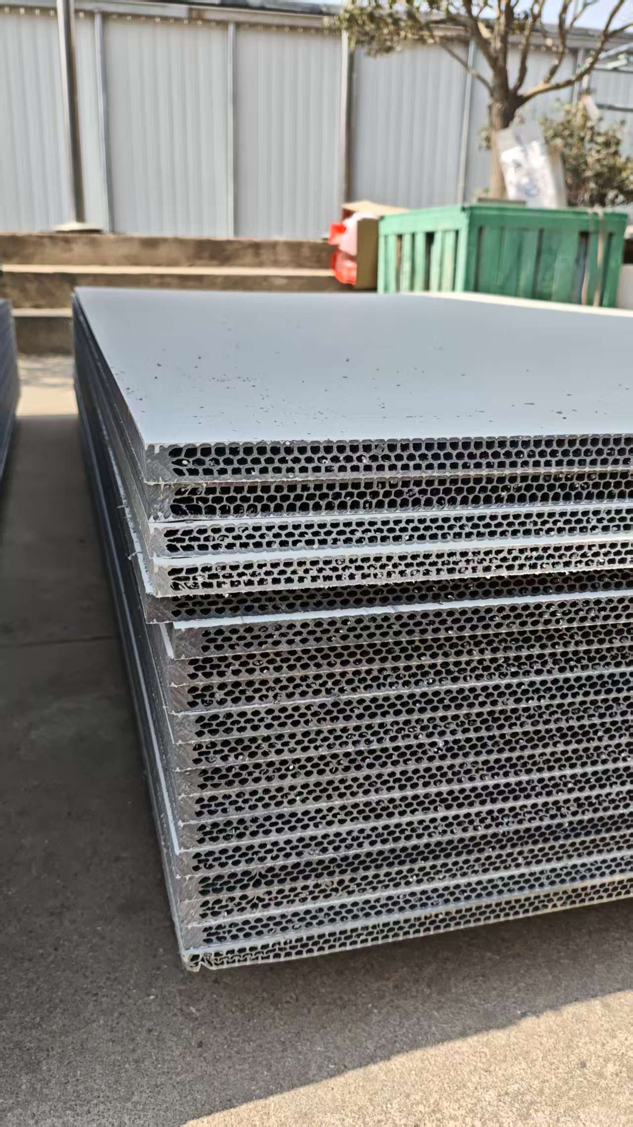 Grey hollow plastic formwork panels with visible honeycomb core structure stacked outdoors at factory yard