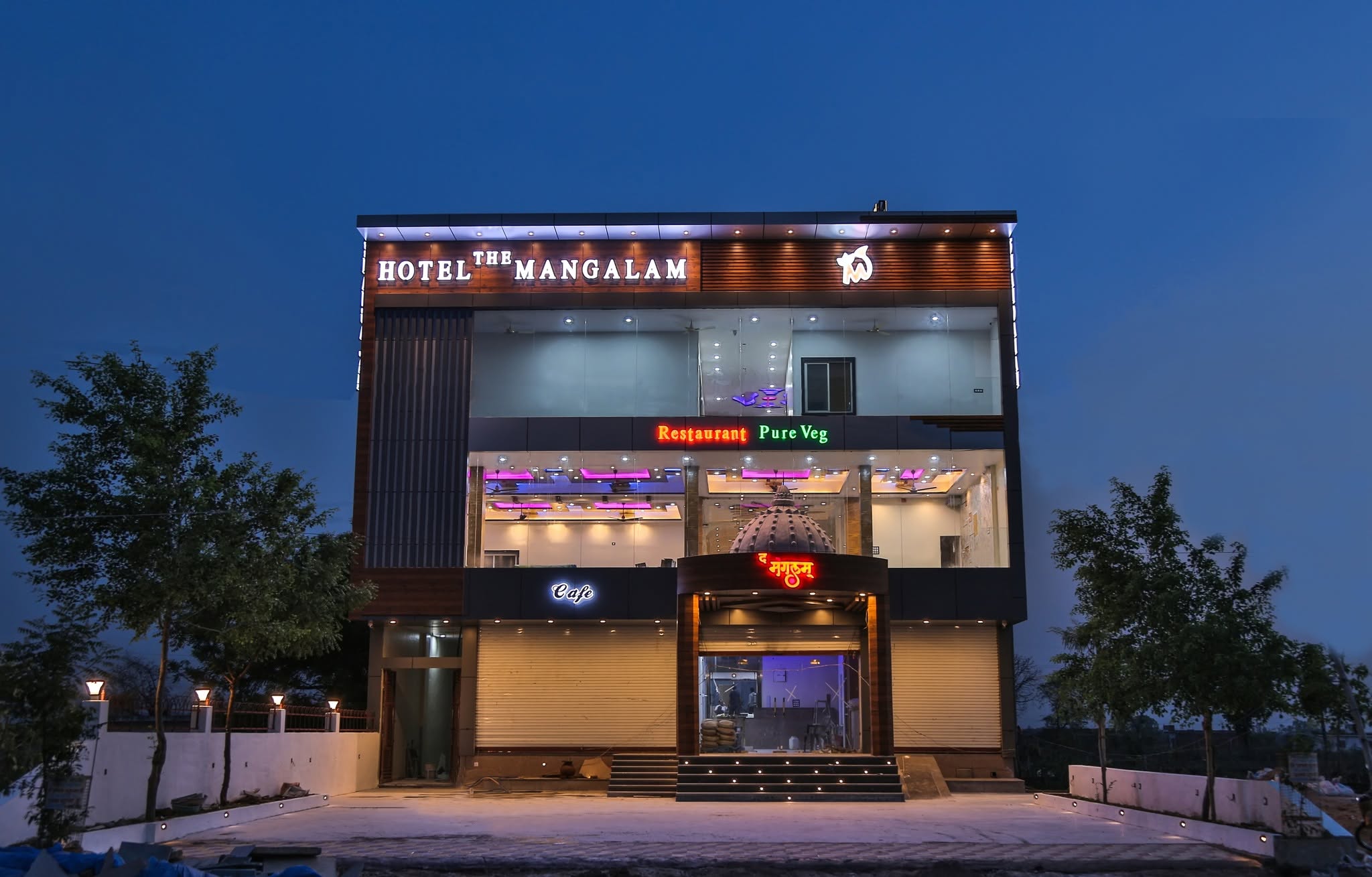 The Mangalam Hotel illuminated three-storey building at night showing the fine dining restaurant in Chhatarpur with Restaurant Pure Veg and Cafe signage visible on the exterior in Nowgong