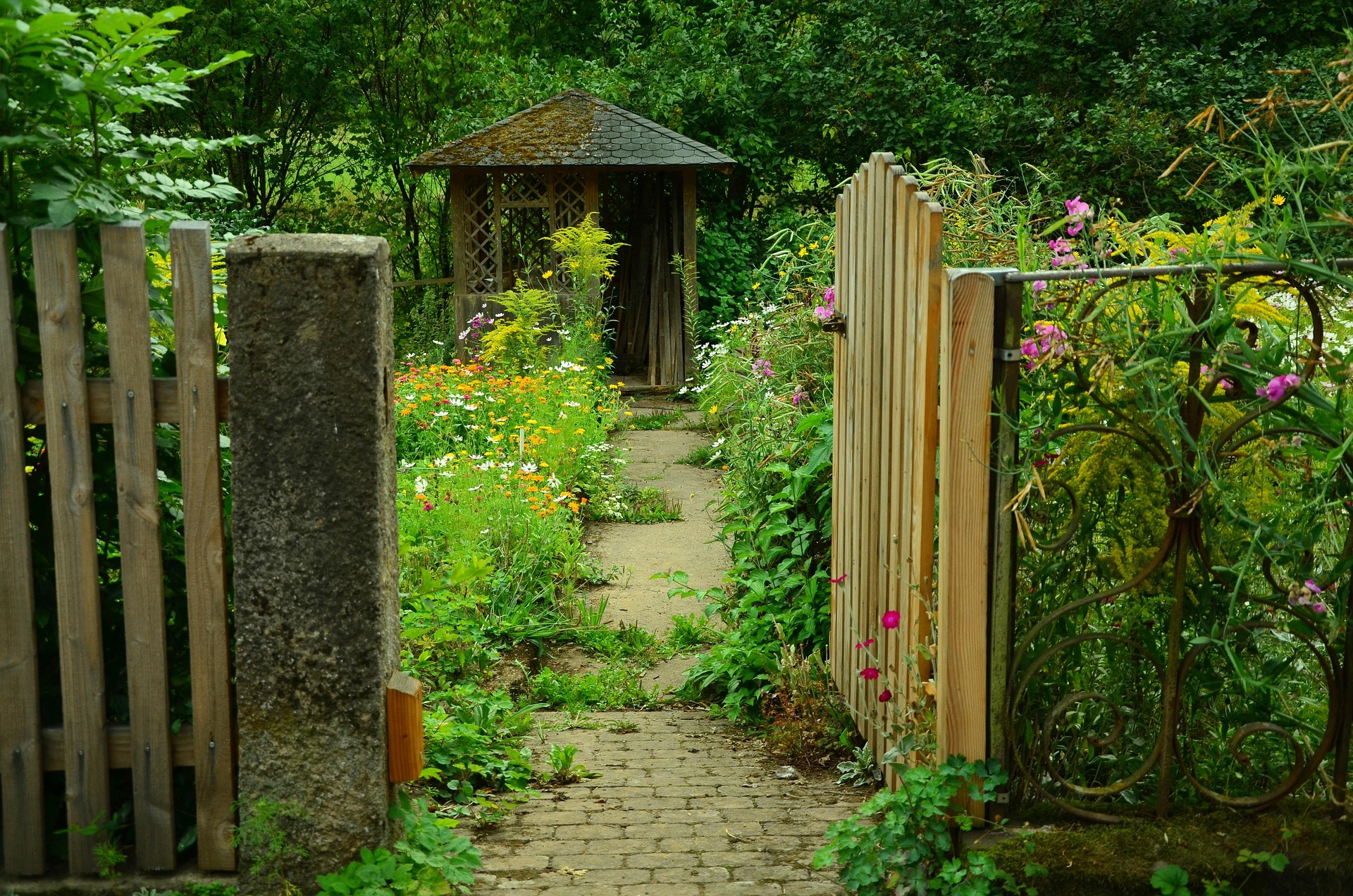 Corporate campus entrance gardens with stone pathway leading to wooden gazebo surrounded by seasonal flowers and greenery