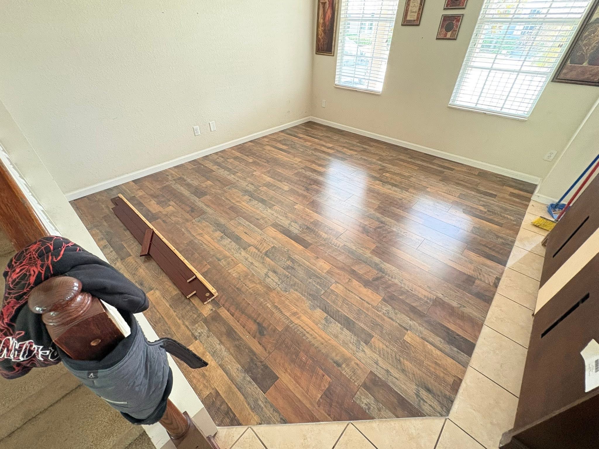 Interior space with wood-look flooring installation, stairway with railing, and wall art — E P Herrera Construccion