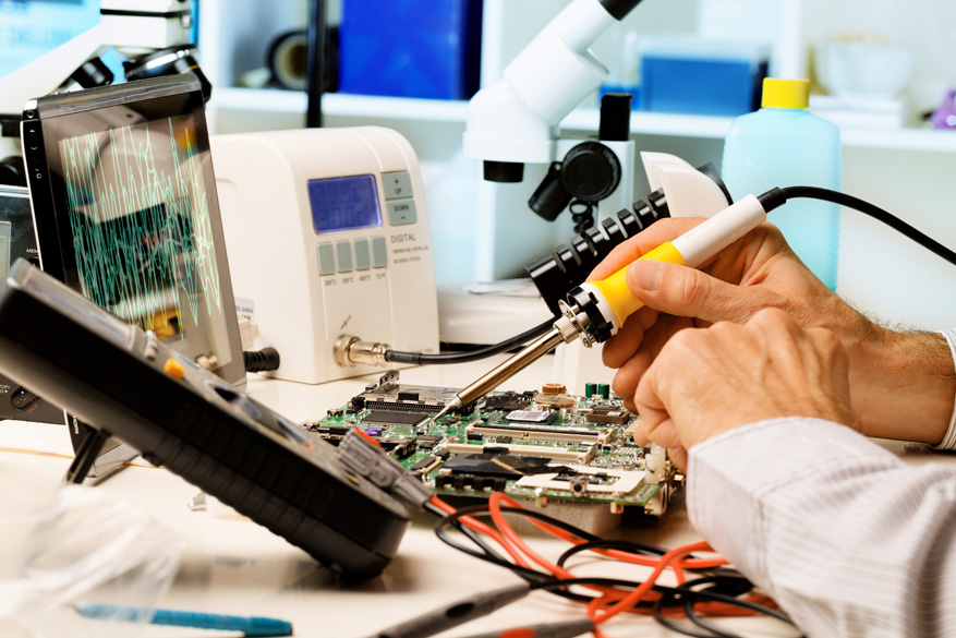 Technician repairing a circuit board with a soldering iron in a lab