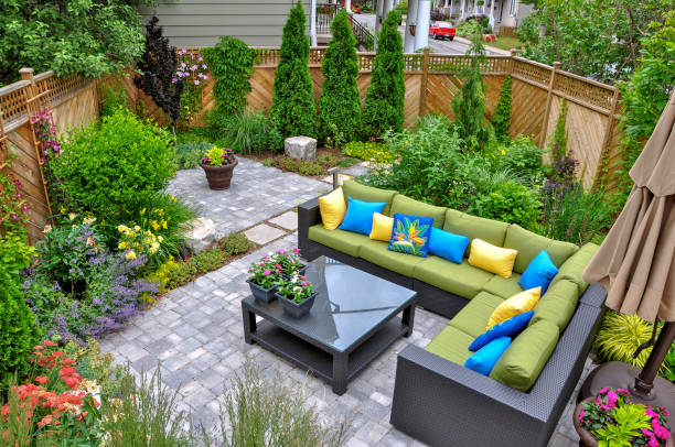 Outdoor patio living space with L-shaped green sofa colorful cushions and garden surroundings
