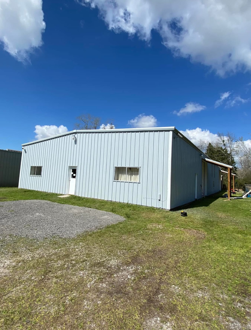 Light blue metal structure building with standing seam roof installed by The Handyman Guys LLC