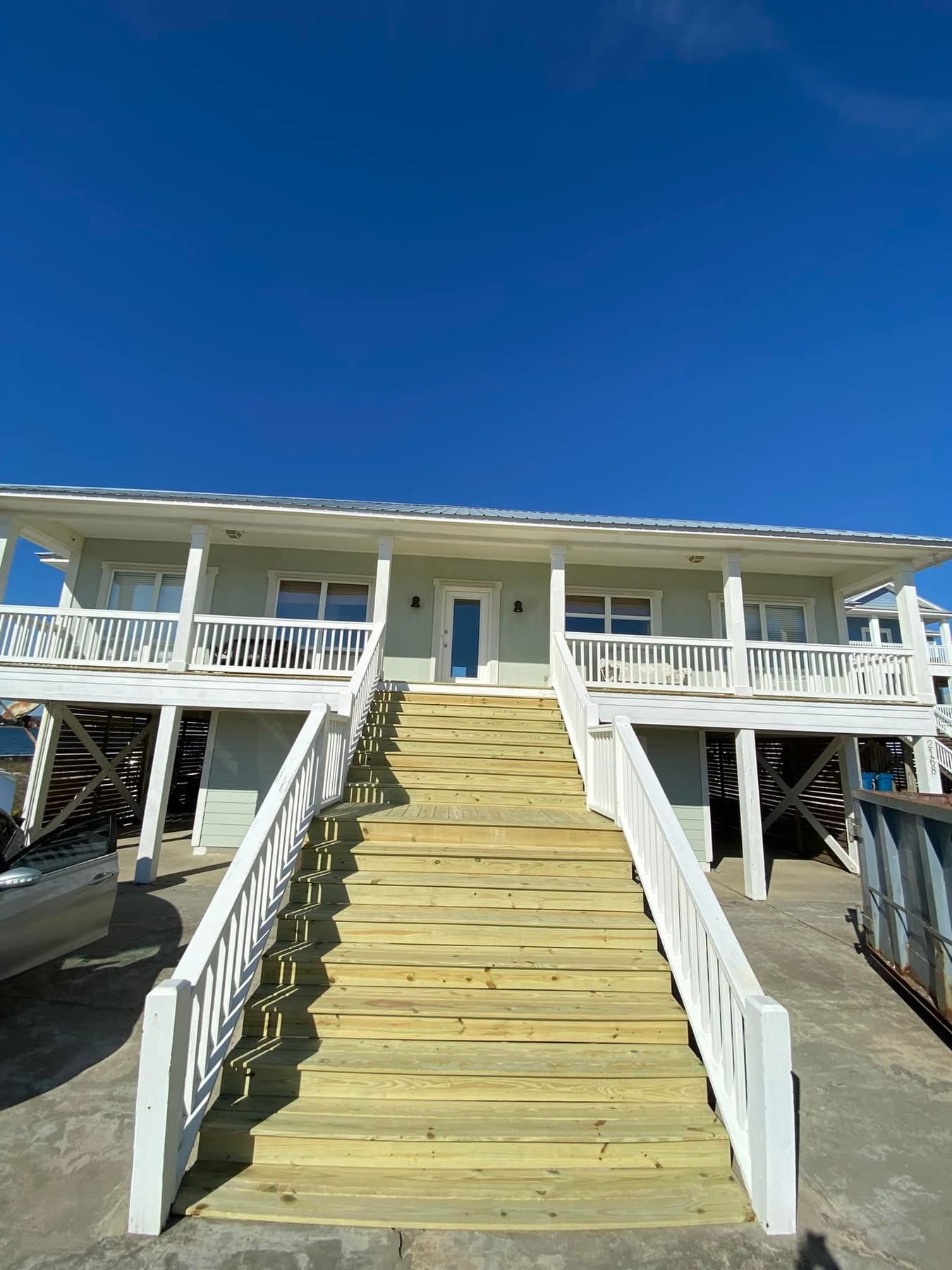 Elevated coastal home with wooden stairs and open foundation, built for Gulf Coast flood and storm conditions