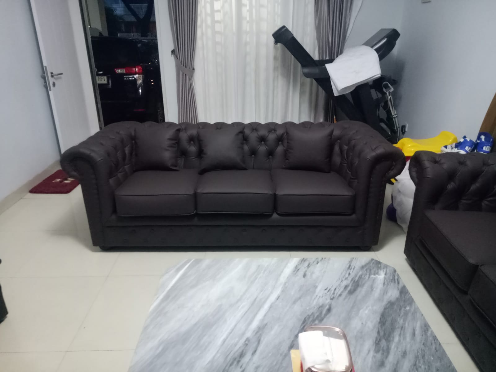 Ruangan dengan set sofa warna coklat tua dan meja kopi marmer