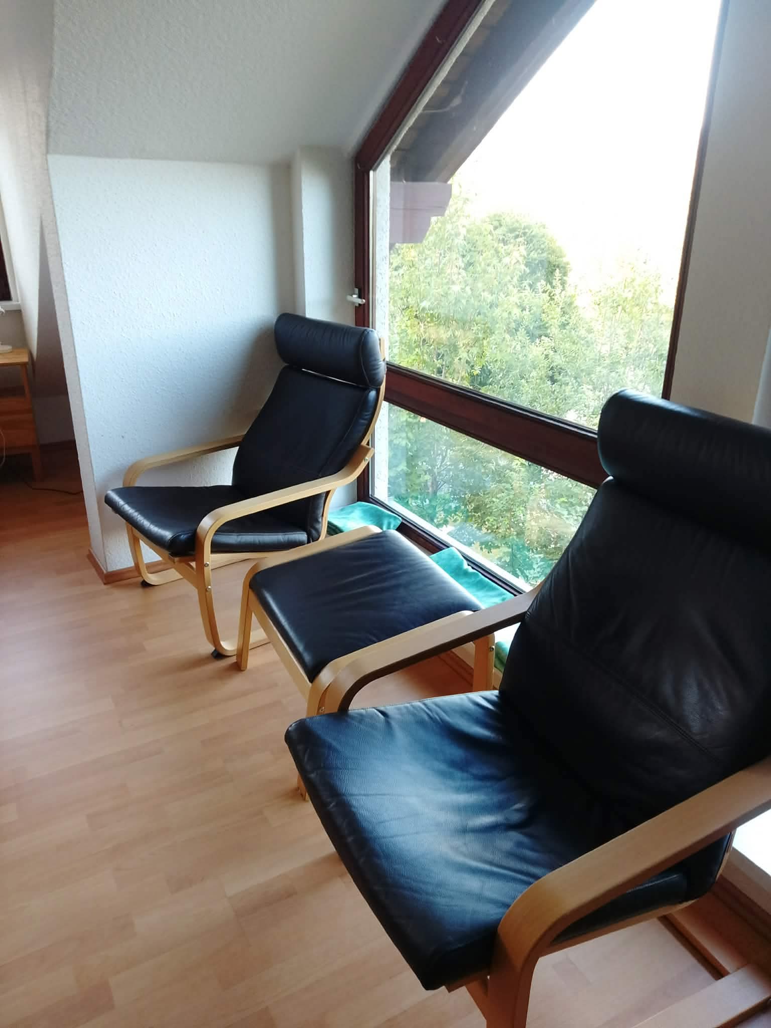Helles Wohnzimmer mit schwarzen Ledersessen