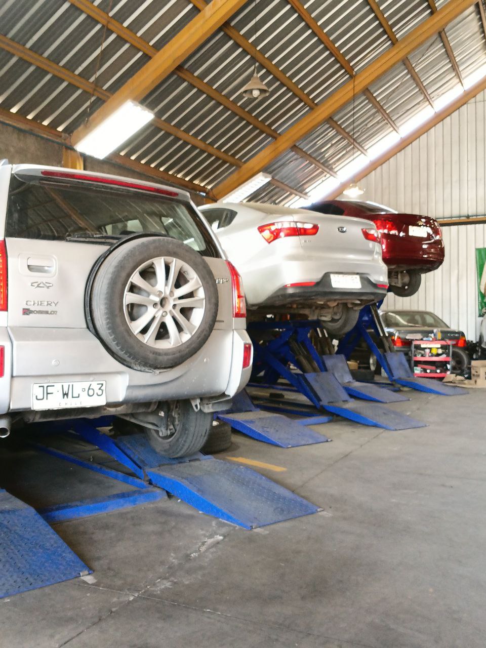 Vista de vehículos en elevadores azules en el taller mecánico