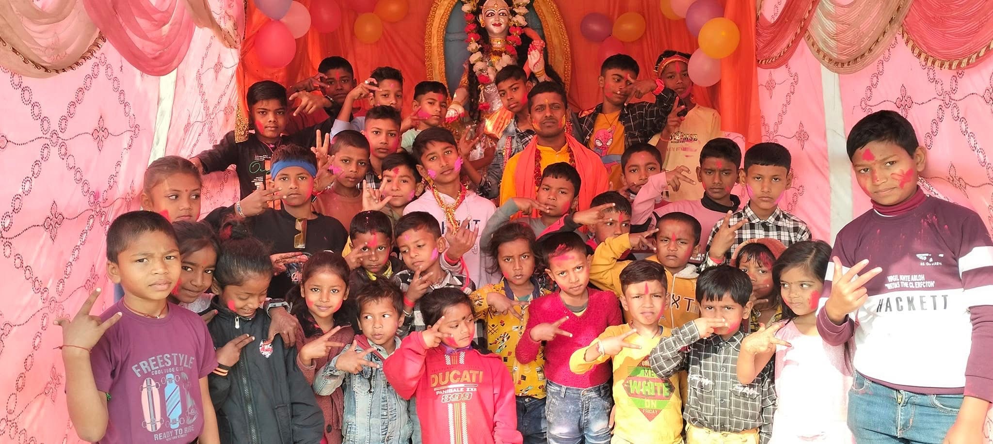 Children in colorful celebration with deity statue