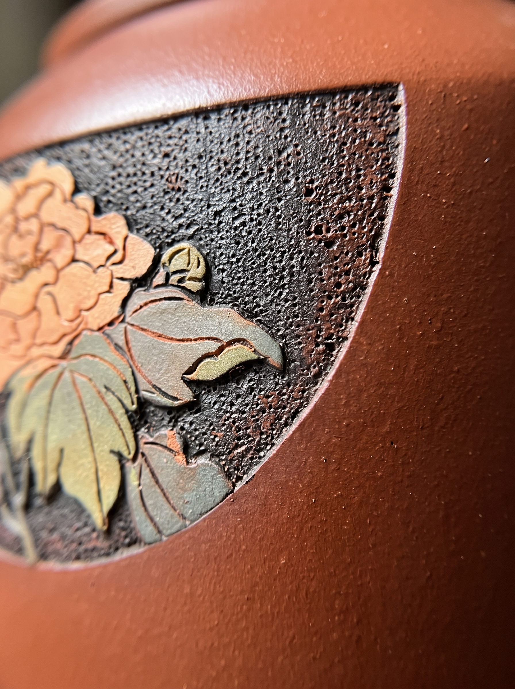 Macro view of a carved peony relief on a polished brown-red Zitao surface