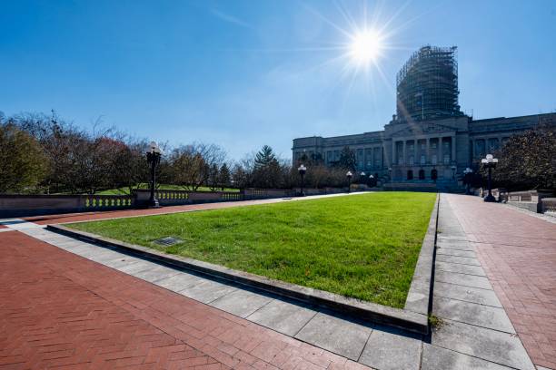 Expansive green Kentucky bluegrass lawn with red and gray walkways, classic building with scaffolding and vintage street lamps in clear sunny weather