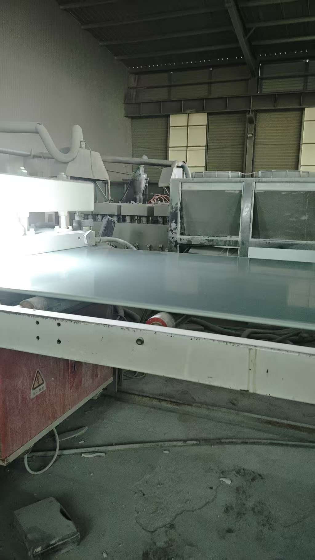 Conveyor belt transporting finished PVC panels through quality inspection station
