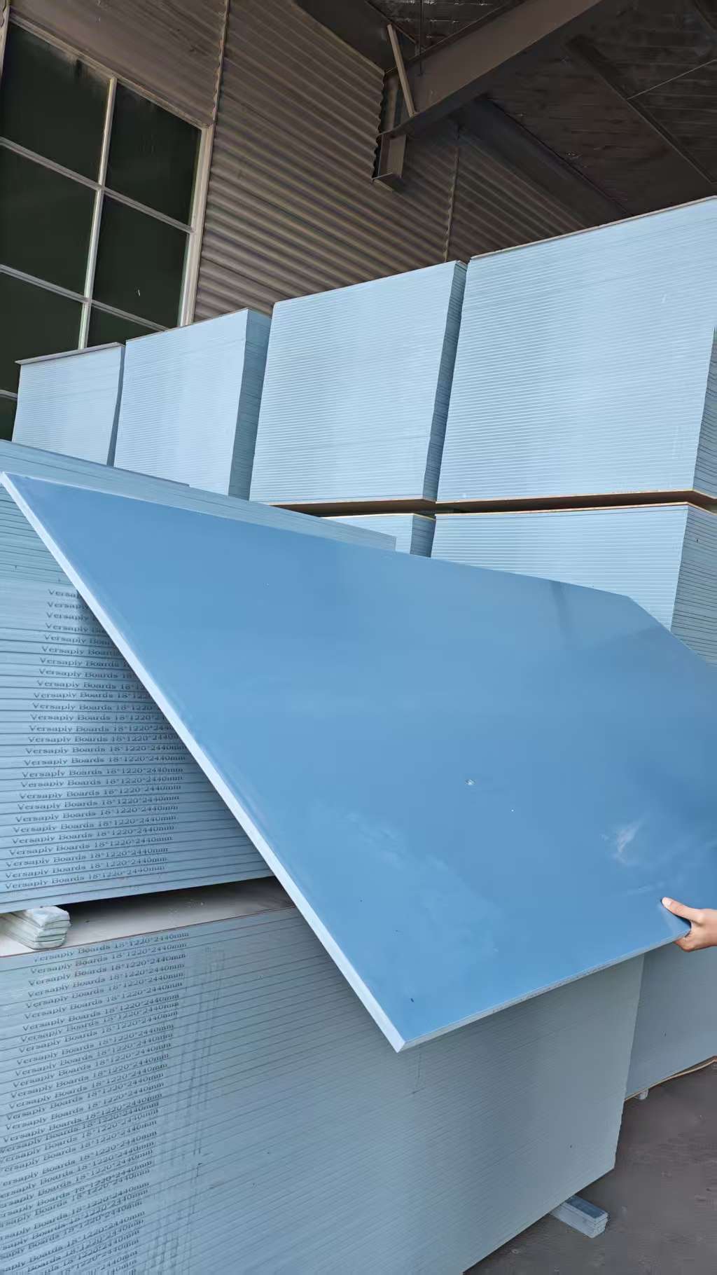 Worker holding PVC beam formwork panel in warehouse storage area