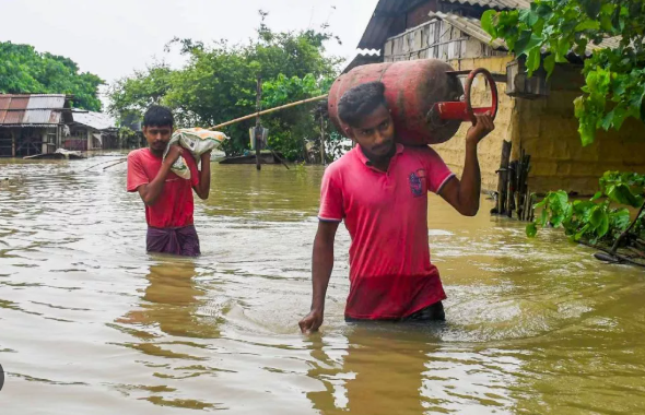 Men wading through chest-deep flood water carrying relief supplies