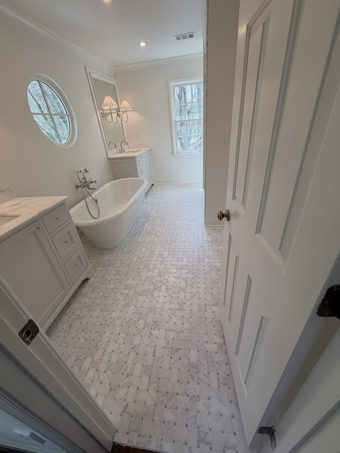 White bathroom with freestanding tub and mosaic floor