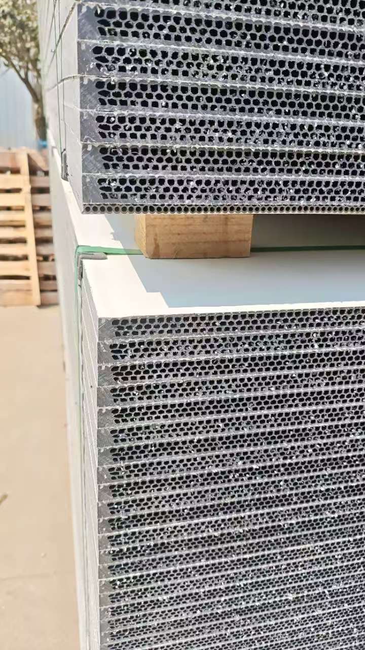 Outdoor stacked hollow plastic formwork panels with honeycomb structure secured by green straps on wooden pallets
